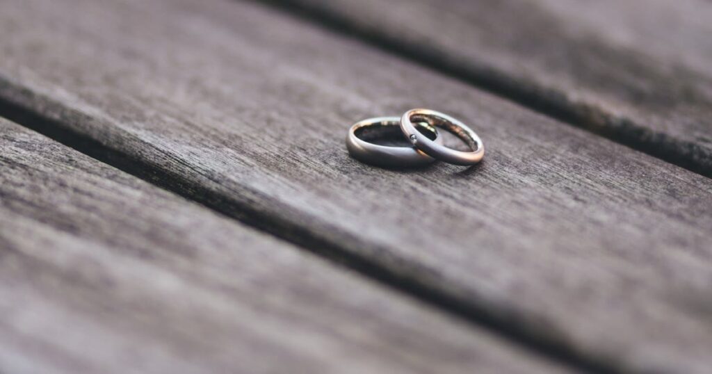 Duas alianças de casamento sobre uma mesa de madeira, simbolizando o divórcio