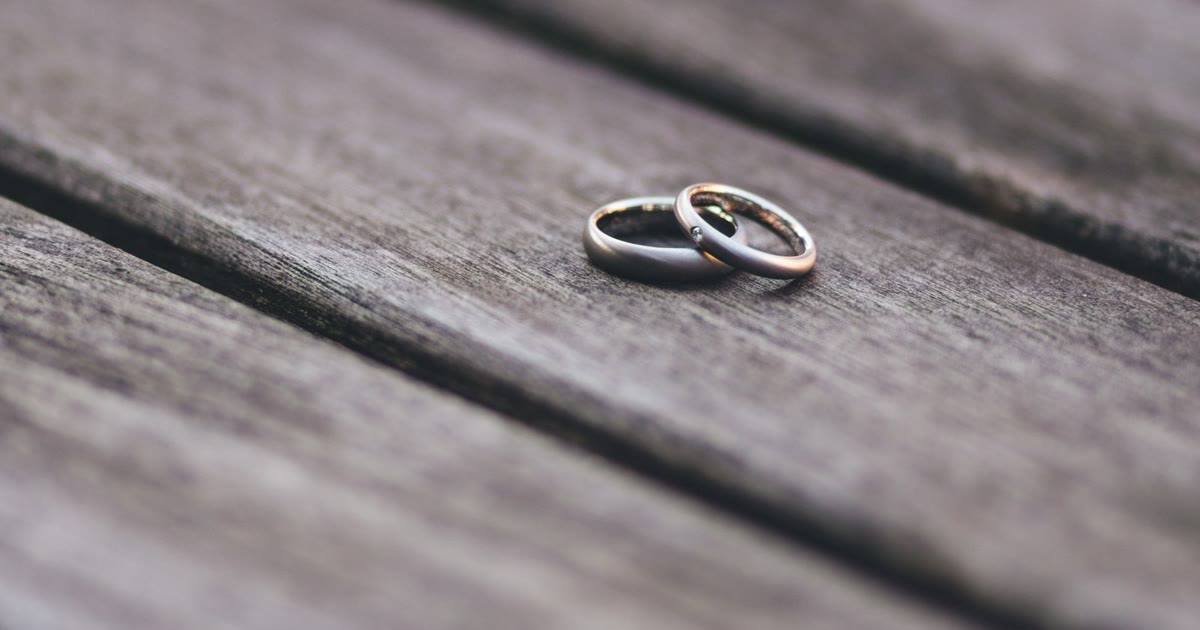 Duas alianças de casamento sobre uma mesa de madeira, simbolizando o divórcio